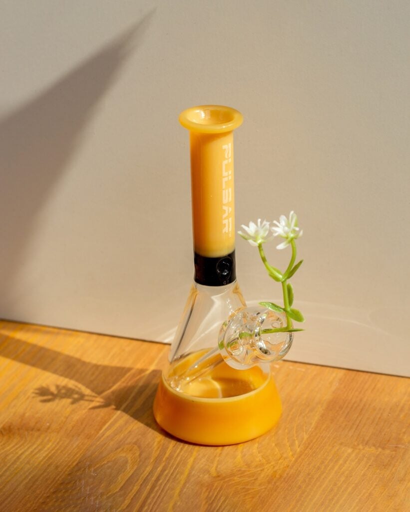 Yellow beaker-shaped bong left on the floor.