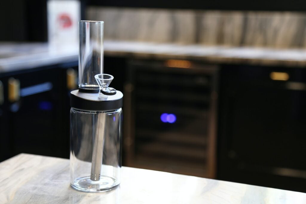 A clear plastic bubbler bong sitting on a wooden table.