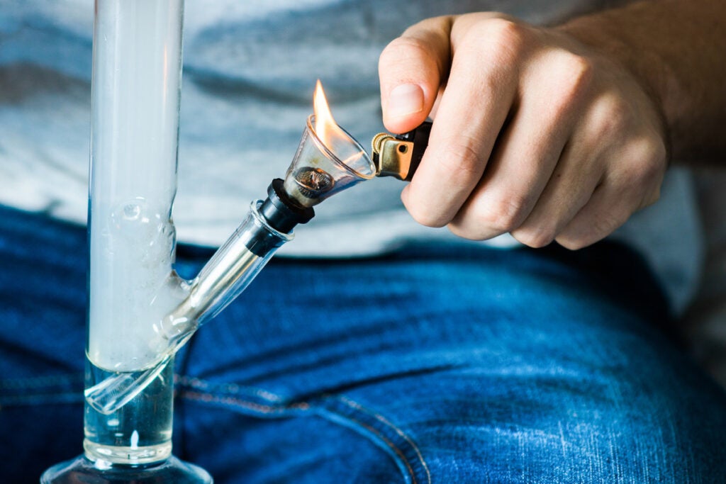 Straight tube bong with a guy lighting the bowl.