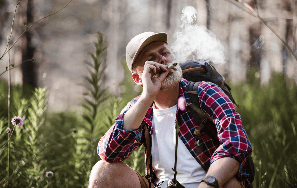 Elderly man enjoying a huge joint outdoors.