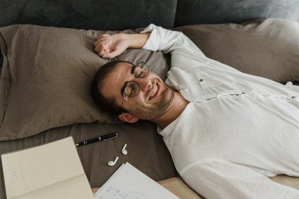 Middle-aged man on his bed laying down with a grin. 