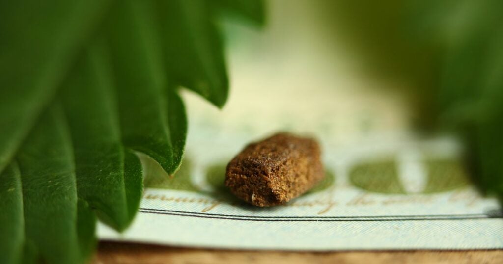 A piece of hashish sitting on light green fabric.