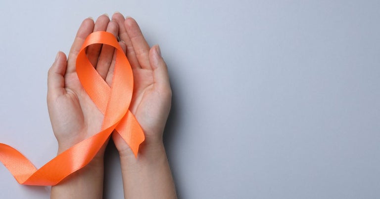 Two hands holding an orange ribbon that represents multiple sclerosis.