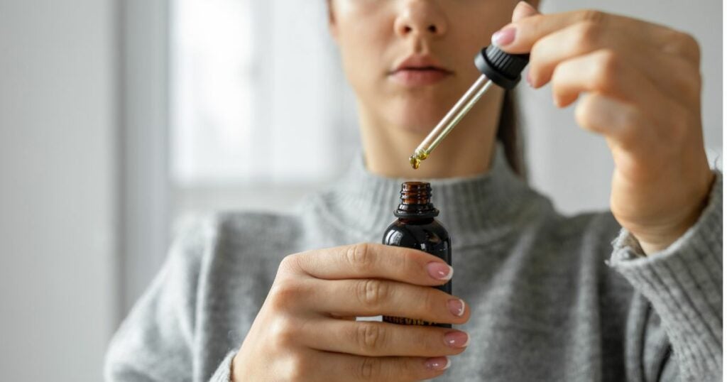 Best-cannabis-strain-woman-holding-a-bottle-drops-oil-CBD-