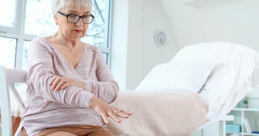 Elderly woman - Parkinson's disease - taking her hand - shaking - arm