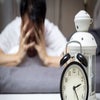 Man with Insomnia covering his head with his hands - bed - clock