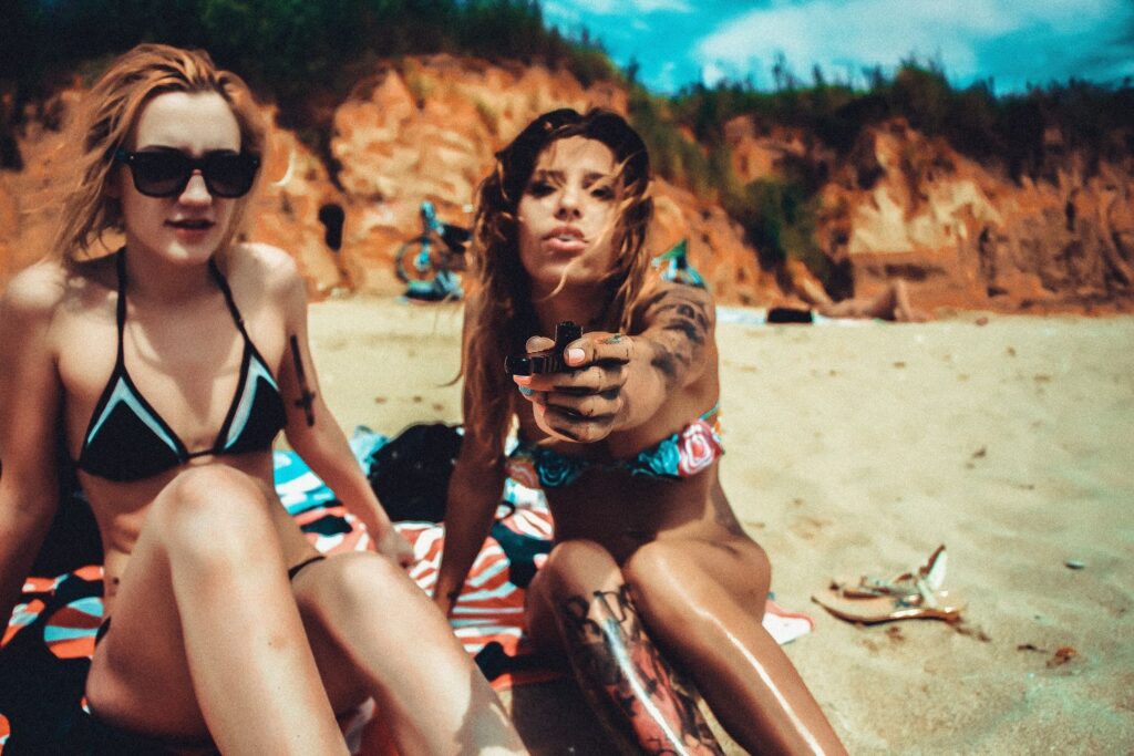 Travelling bikini girls smoking weed on the beach and passing on the bong.