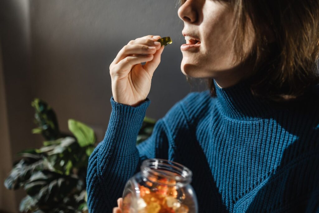 middle aged lady eating gummy bear weed edibles from a jar 