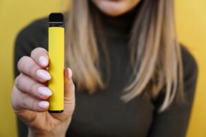 Young attractive woman with blond hair showing off her yellow disposable weed vape pen