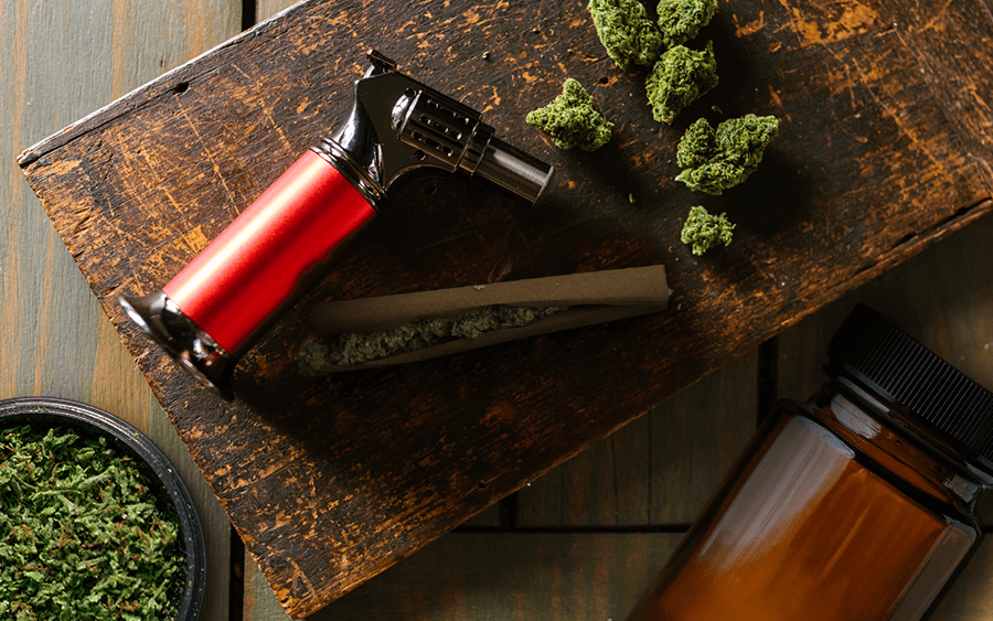 This image features essentials in a weed kit - torch lighter, hemp wraps, storage container, and grinder.
