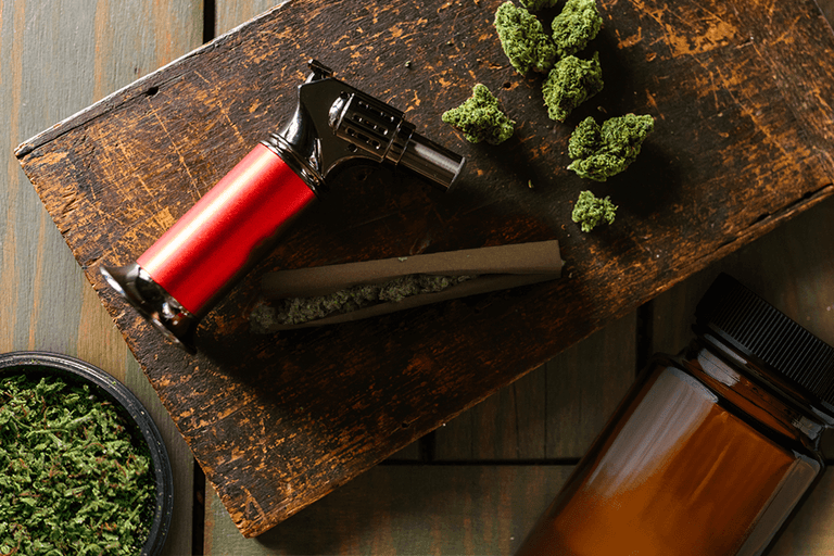 This image features essentials in a weed kit - torch lighter, hemp wraps, storage container, and grinder.