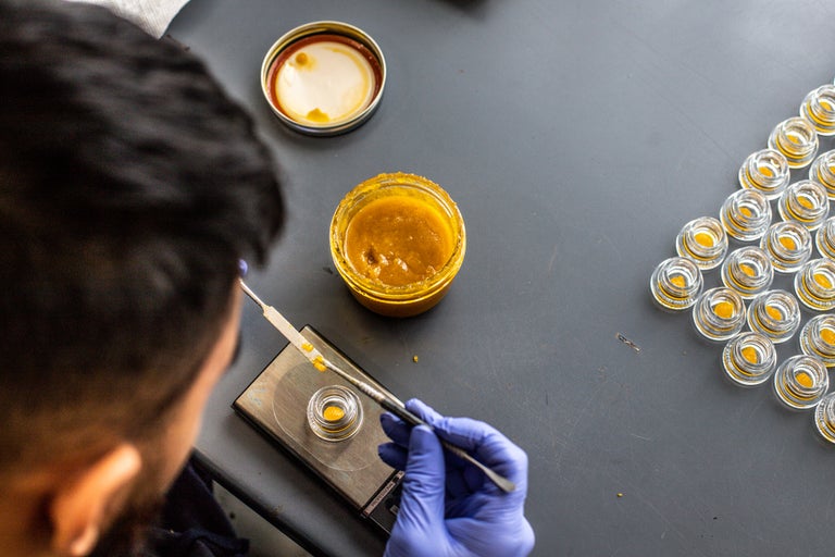Black haired male making Live Resin product by putting it into a glass container.