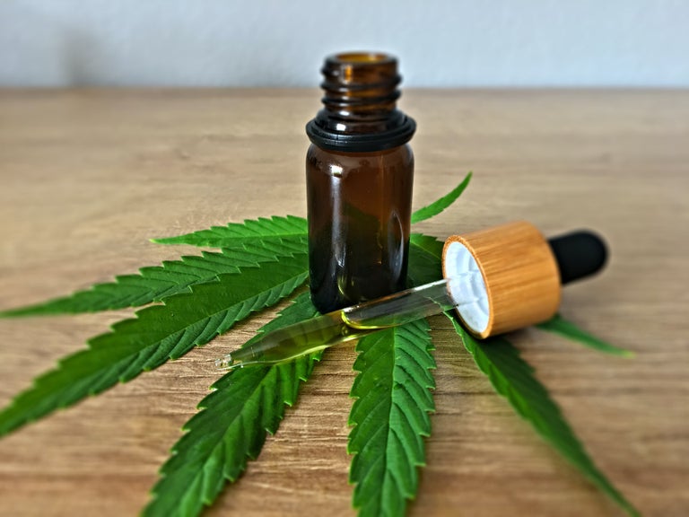 Brown THC syrup bottle on top of a cannabis leaf.
