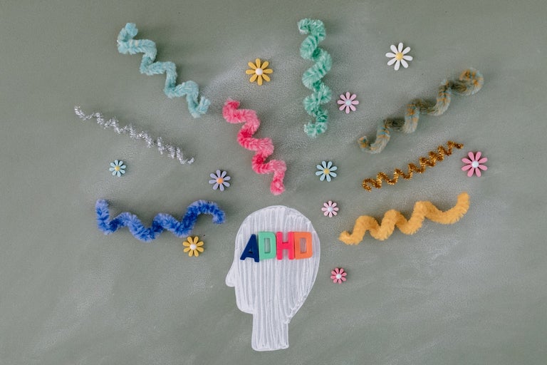 Felt cut out of a head with ADHD written on it. felt lines spring out of the head to visualize many distractions.