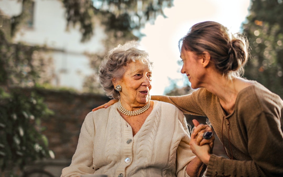 Old lady has osteoporosis and can't stand up. Younger lady is holding her hand to act as support.