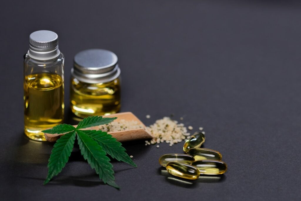 CBD Oil and capsules placed on a black background.