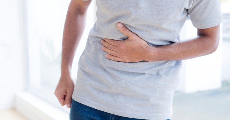 Young man suffering from irritable bowel syndrome, also known as IBS. He is holding his stomach and seems to be in pain.