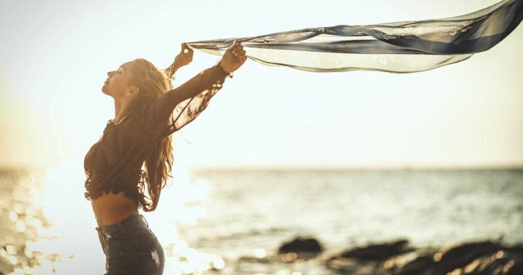 Young woman on a beach with her hands up expressing freedom.