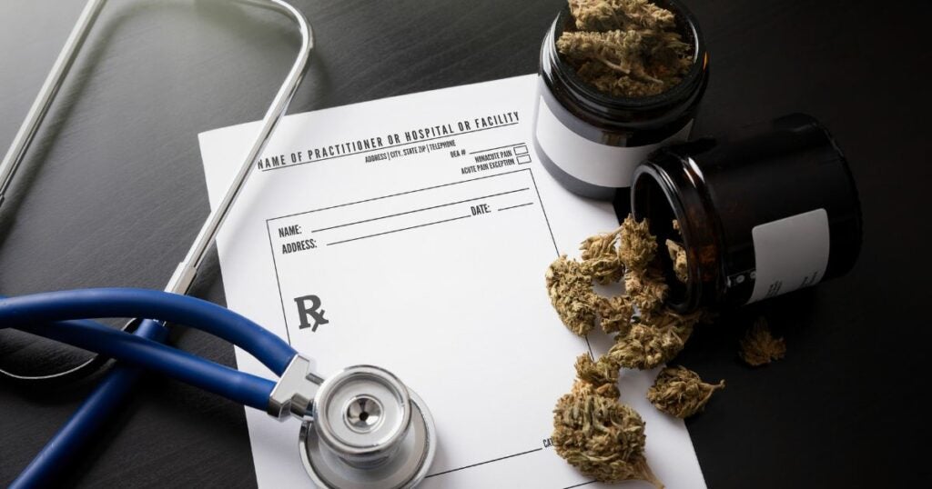 Cannabis for medical use sits on a table alongside medical documents and equipment.