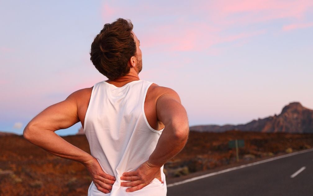 Young man on a run on the road. He is experiencing chronic pain in his back.