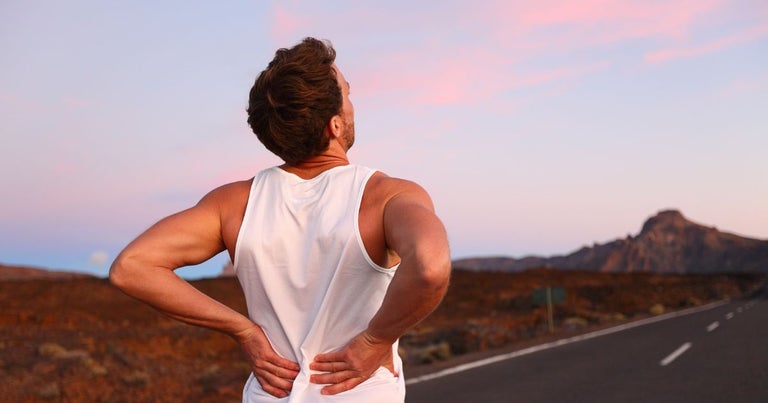 Young man on a run on the road. He is experiencing chronic pain in his back.