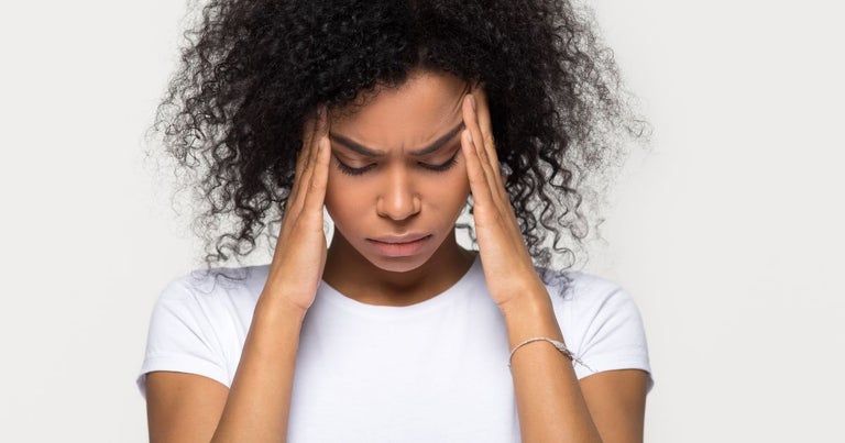 Woman with migraine holding her head with her hands